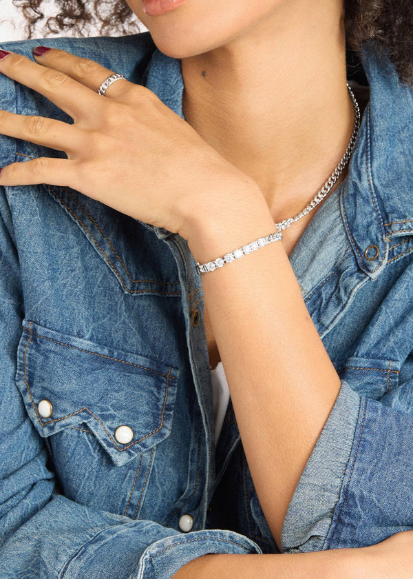 Person wearing a diamond bracelet and ring with a denim jacket