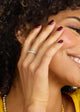 Woman with curly hair covering her face with a hand, wearing a yellow top.