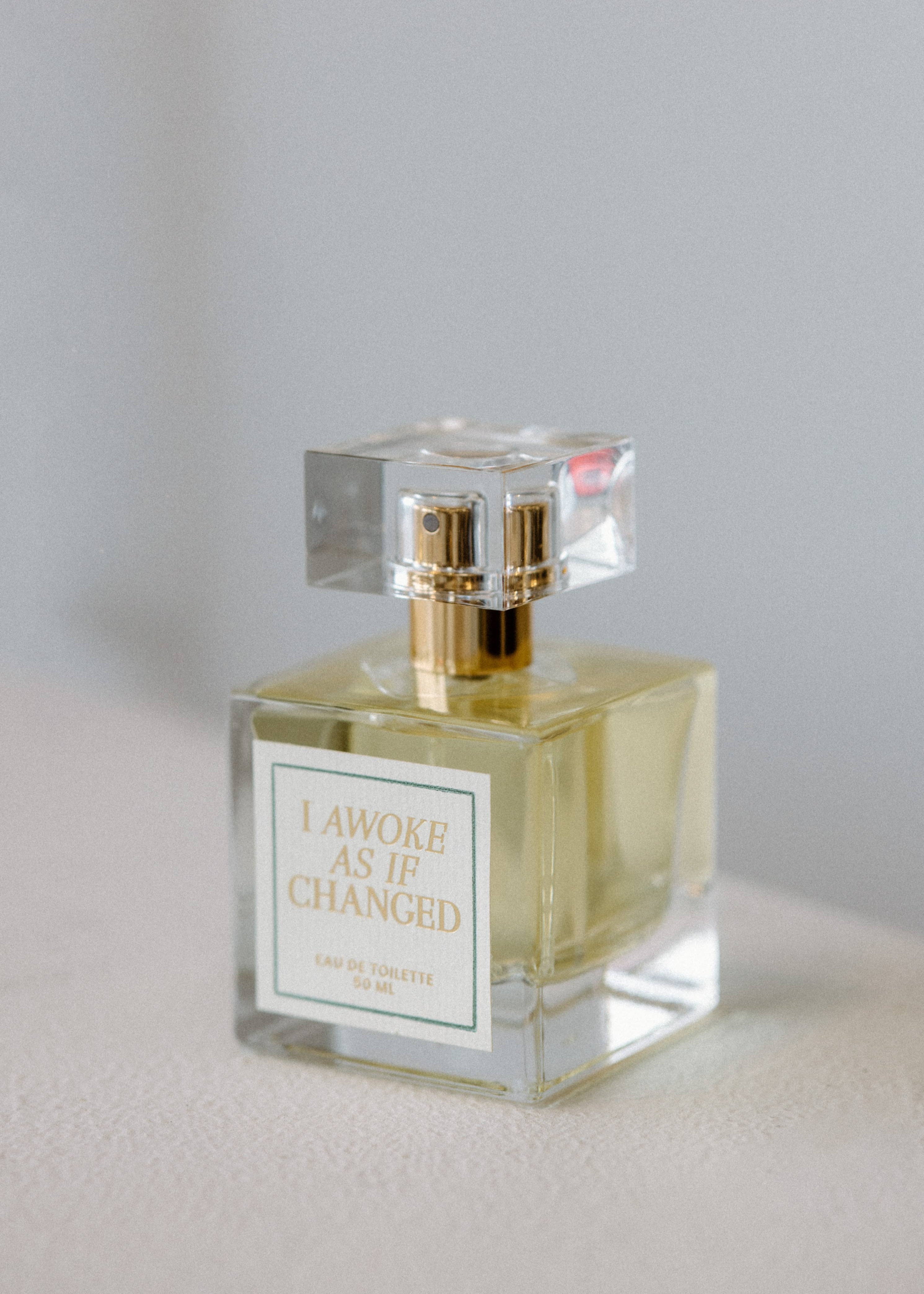 Perfume bottle with gold cap on a light gray background