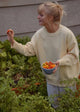 Woman holding a bowl of tomatoes in a garden