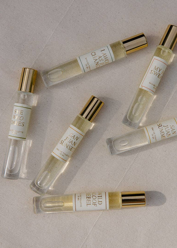 Set of small perfume bottles with gold caps on a beige surface
