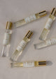 Set of small perfume bottles with gold caps on a beige surface