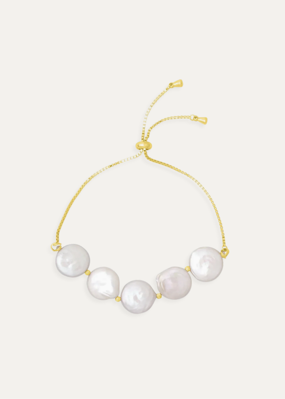 Gold bracelet with pearls on a light gray background