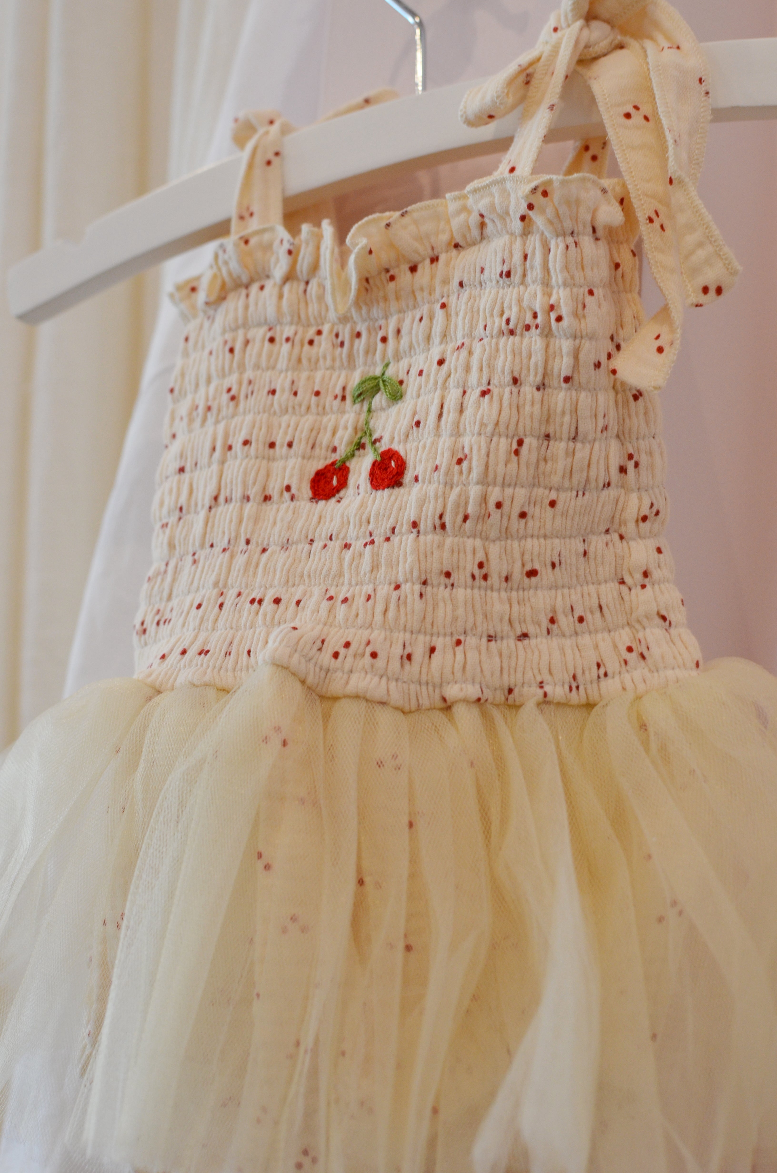 Cream-colored dress with floral embroidery on a mannequin against a light background