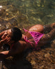 Person lying in clear water wearing a pink bikini
