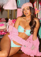 Woman in a colorful outfit with pink and green elements, surrounded by fashion items.